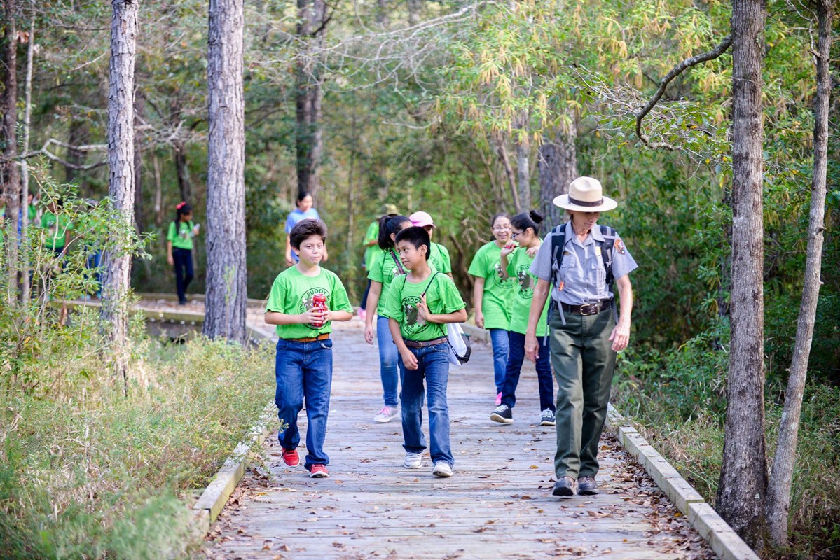 a park ranger leading a group of students hiking on a boardwalk