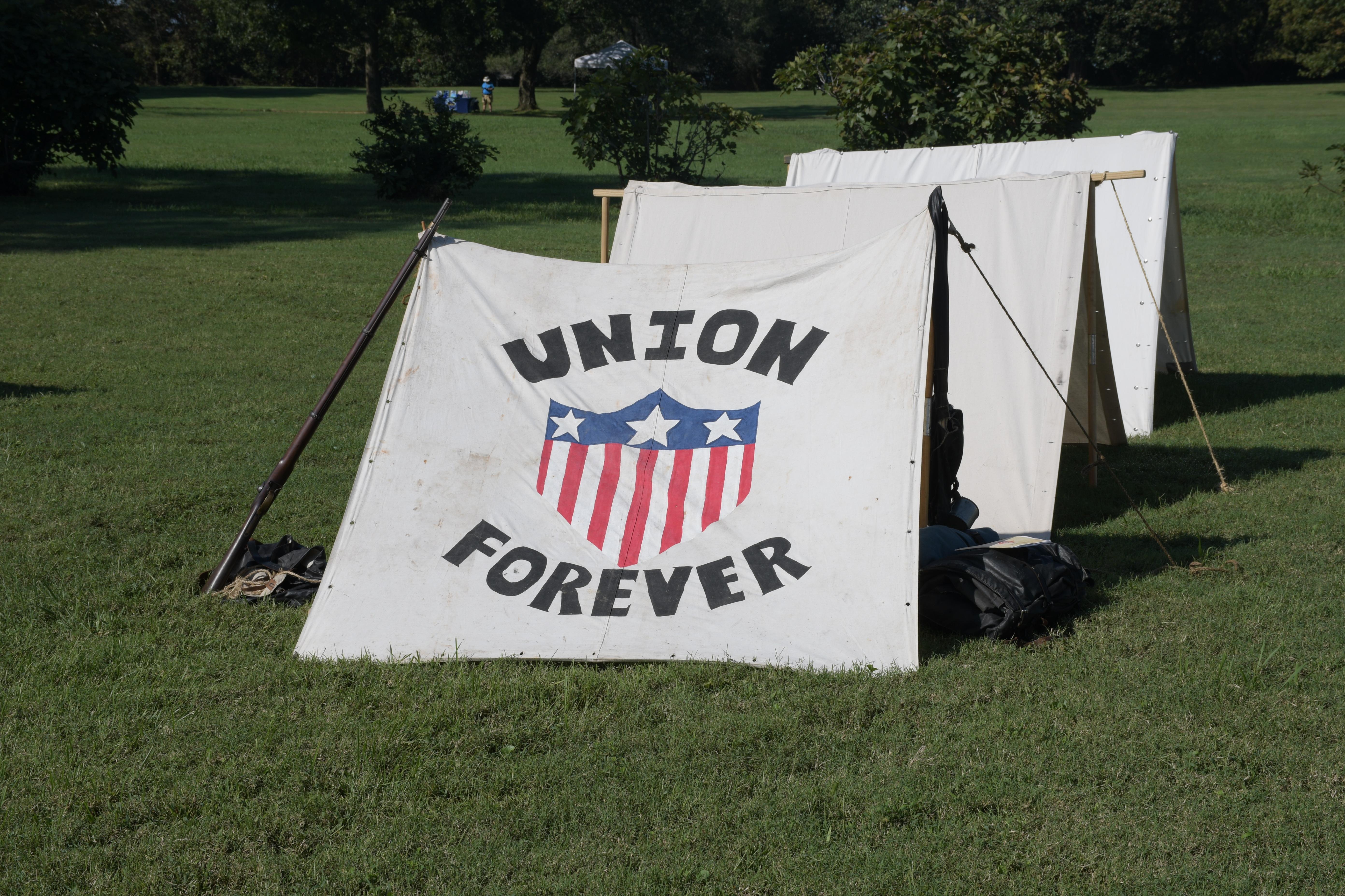 A white canvas tent with a red, white, and blue crest; Bold text around crest reads Union Forever.