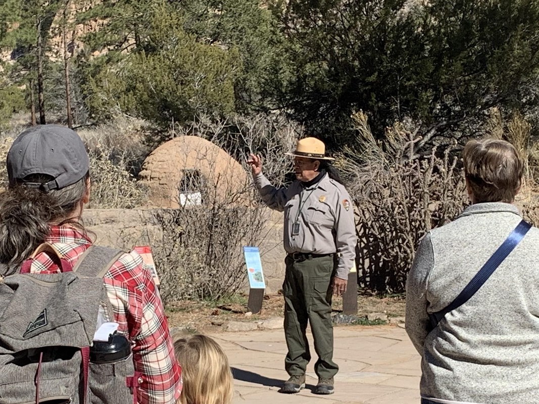 A park ranger stands in front of a group of adults and children.