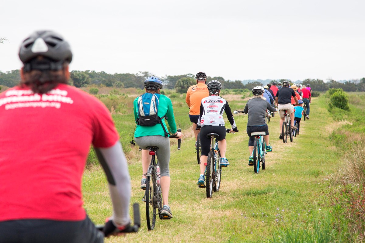 People ride bikes on a grass trail