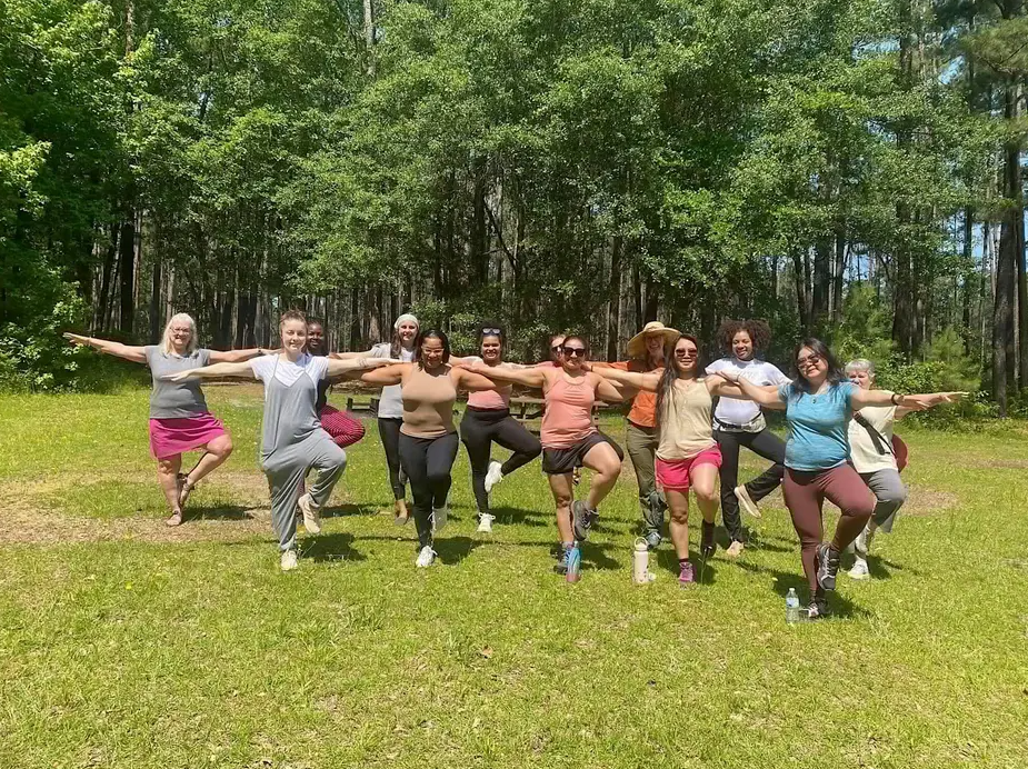 A group of people standing in a field with their arms out in a yoga pose