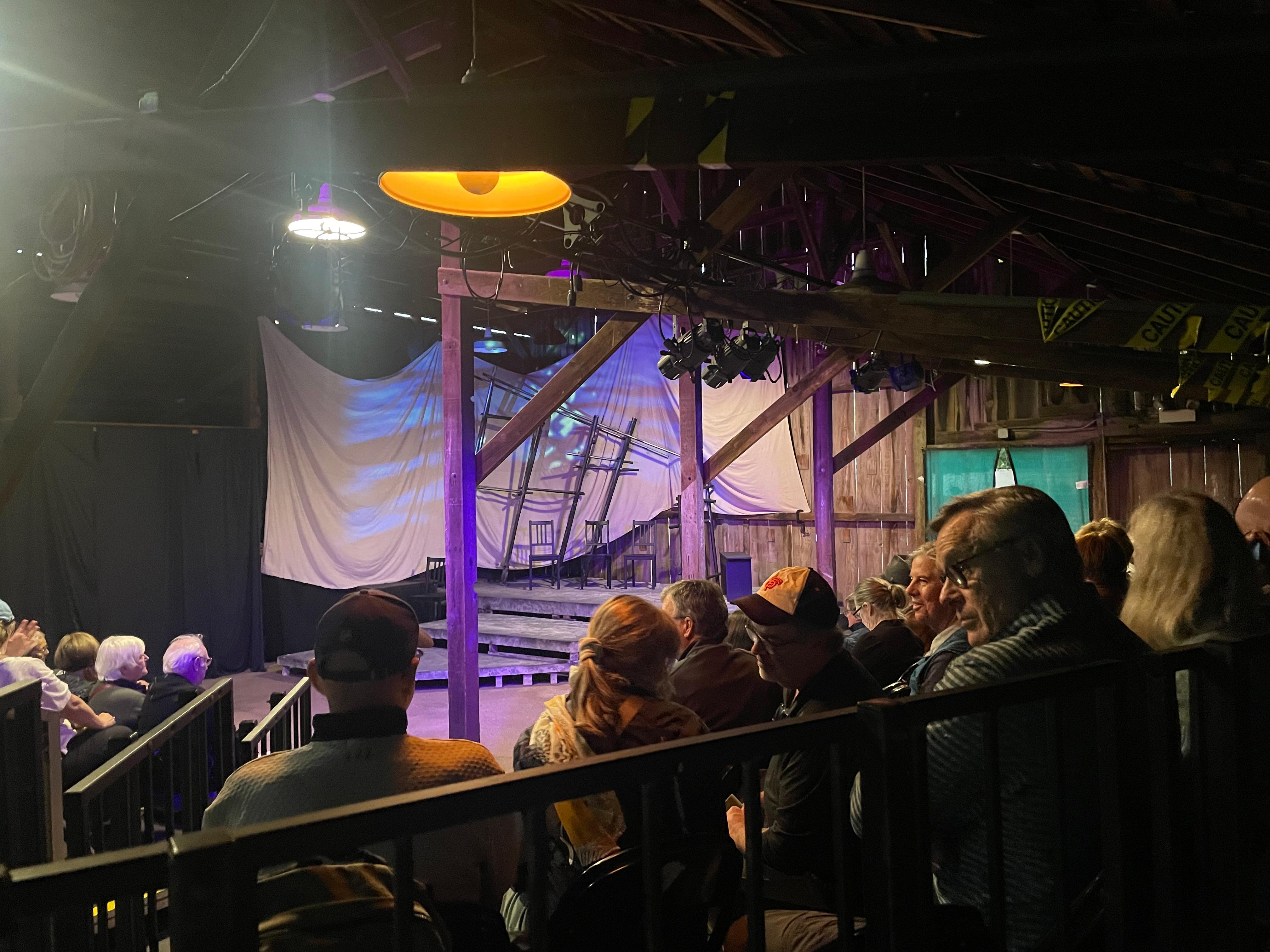 People sit in stadium-style seating in front of a stage.