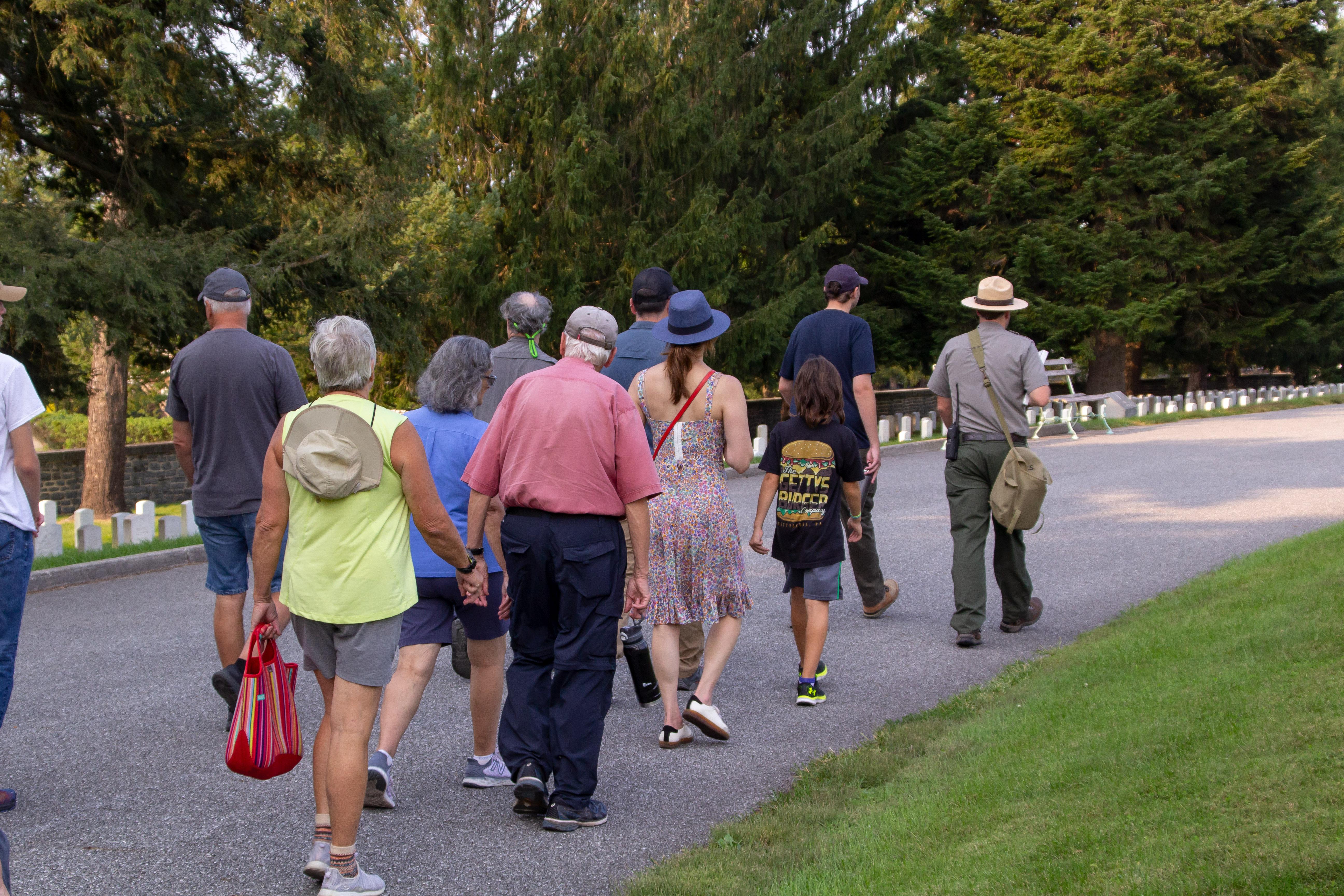 A group of visitors walks with a park ranger in a national cemetery
