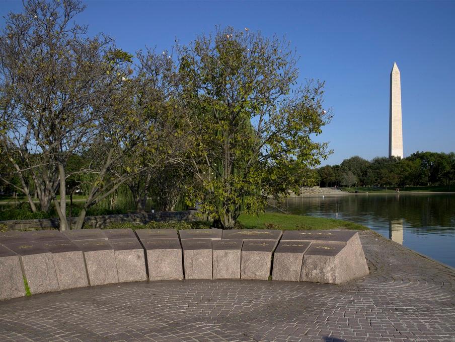 grey colored stone surrounded by trees in the middle of a man made lake