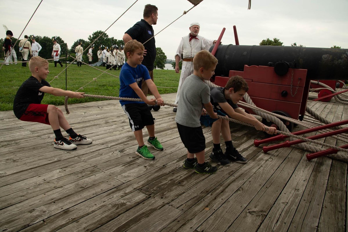 Kids pulling ropes on a cannon carriage.