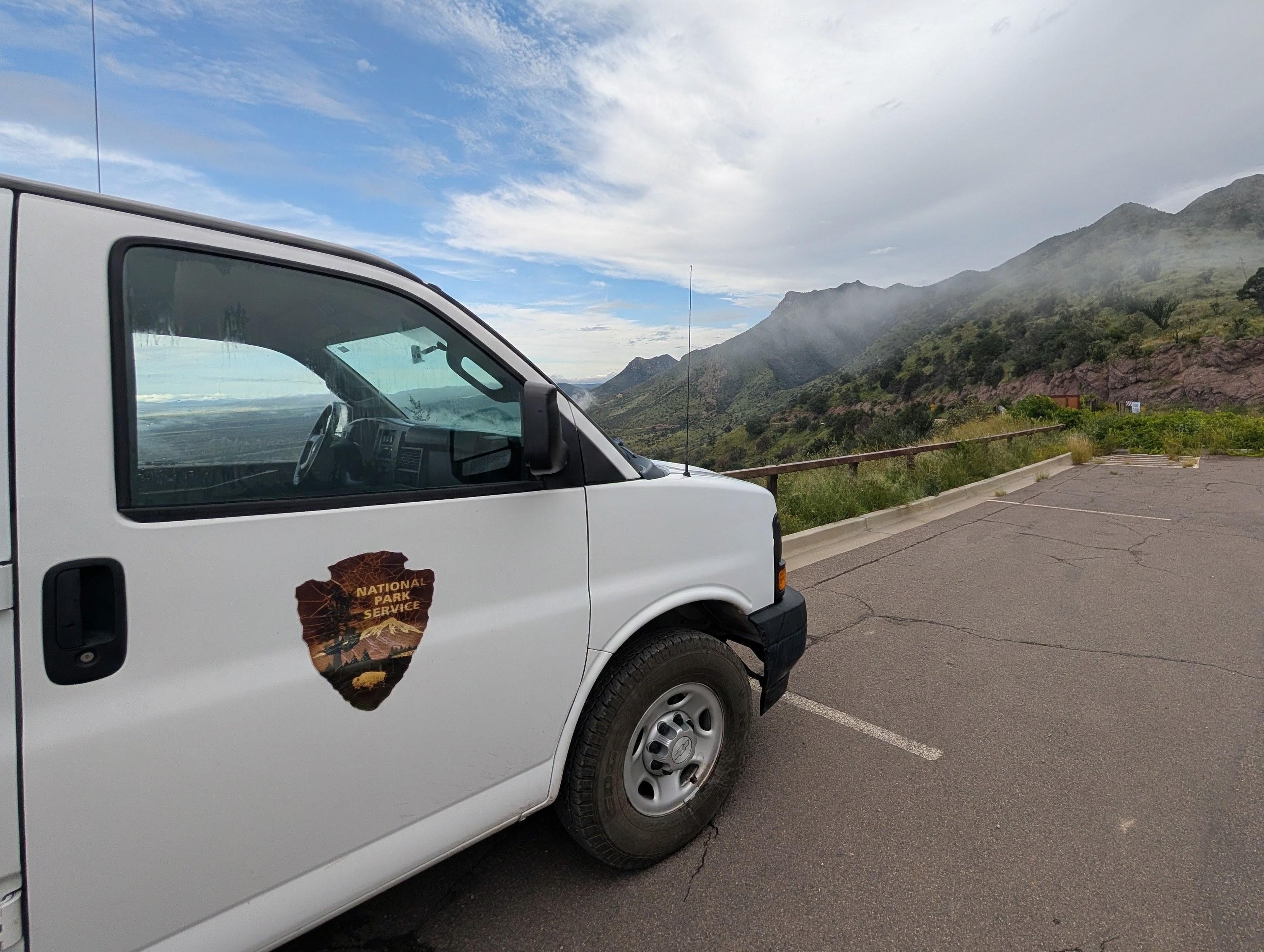 A NPS shuttle van is parked at Montezuma Pass Overlook with views of Joe's Canyon Trail.