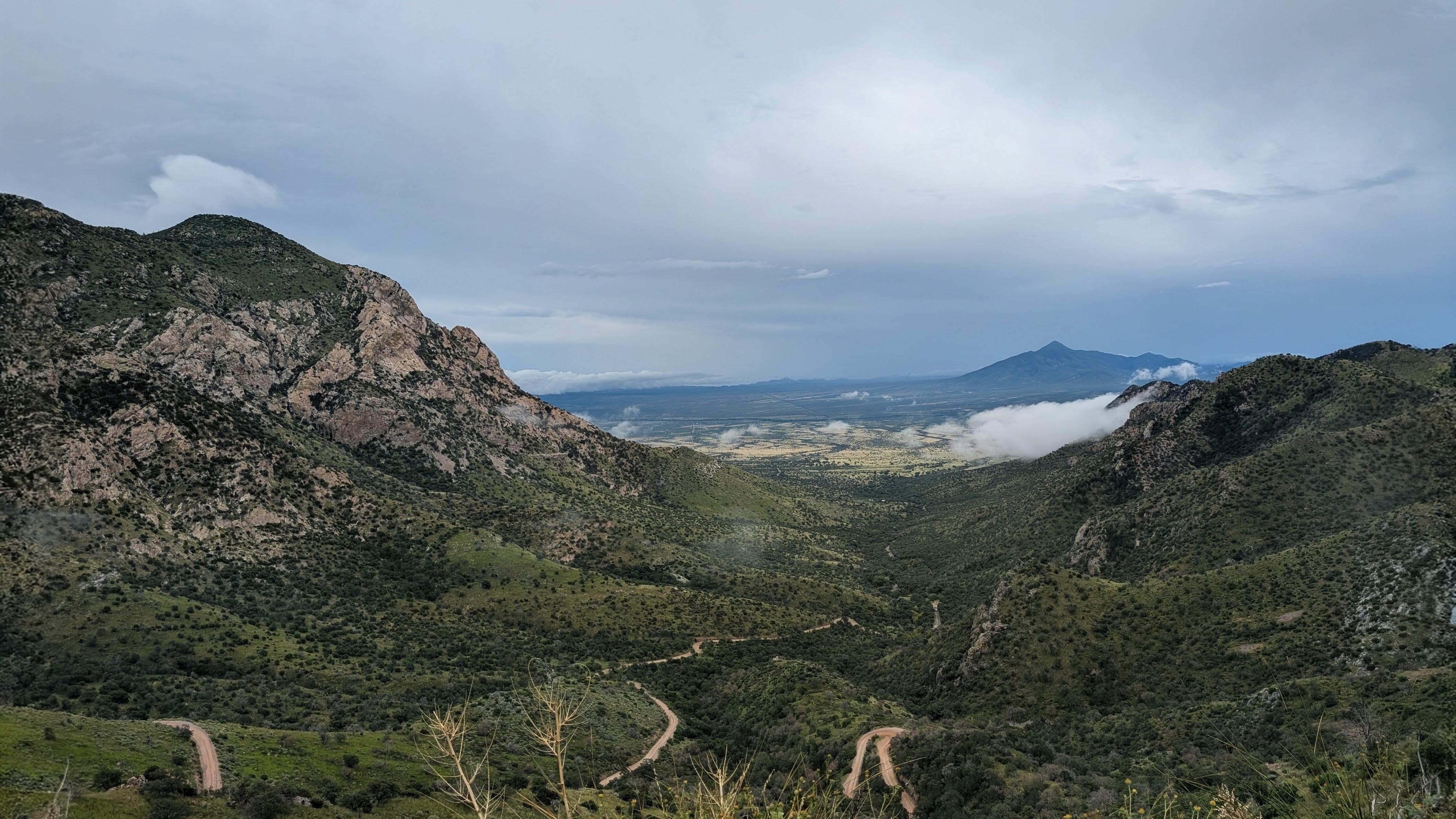 A view from Montezuma Pass Overlook looking east toward a cloudy and rainy San Pedro River Valley.