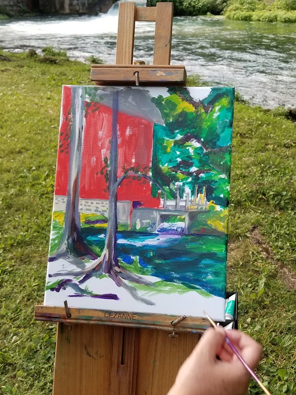 a rough start of an oil painting of alley mill with a painter holding a brush