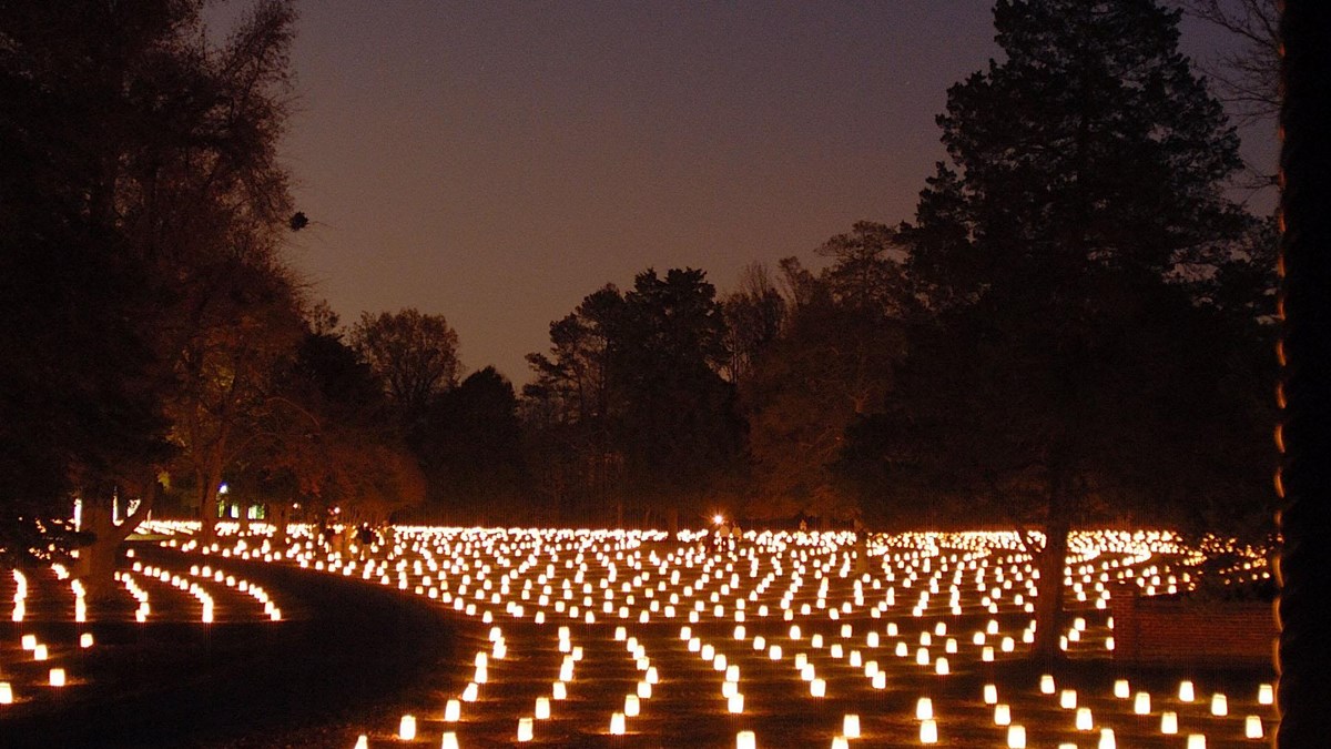 Hundreds of luminaries light up headstones in a cemetery.