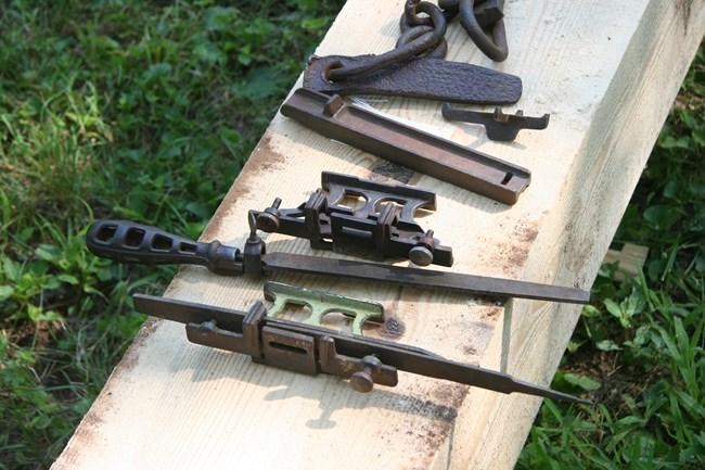 various old iron tools sitting on a wooden bench