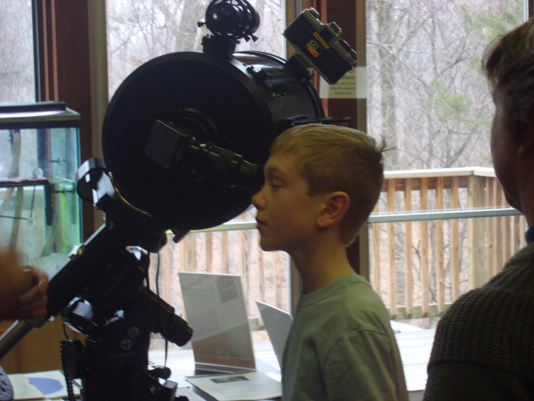 A boy looks through a telescope