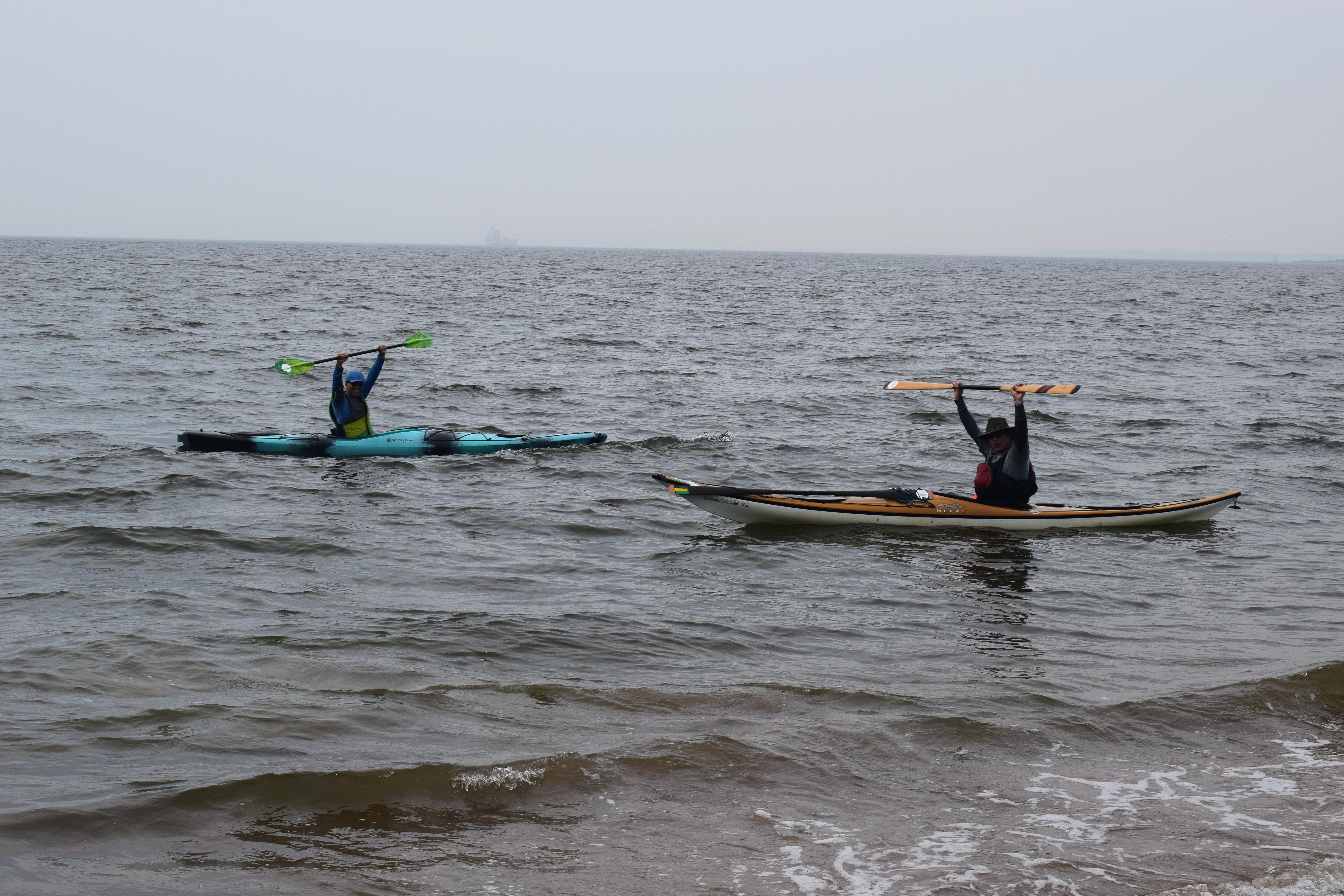 Two kayakers with arms above their heads
