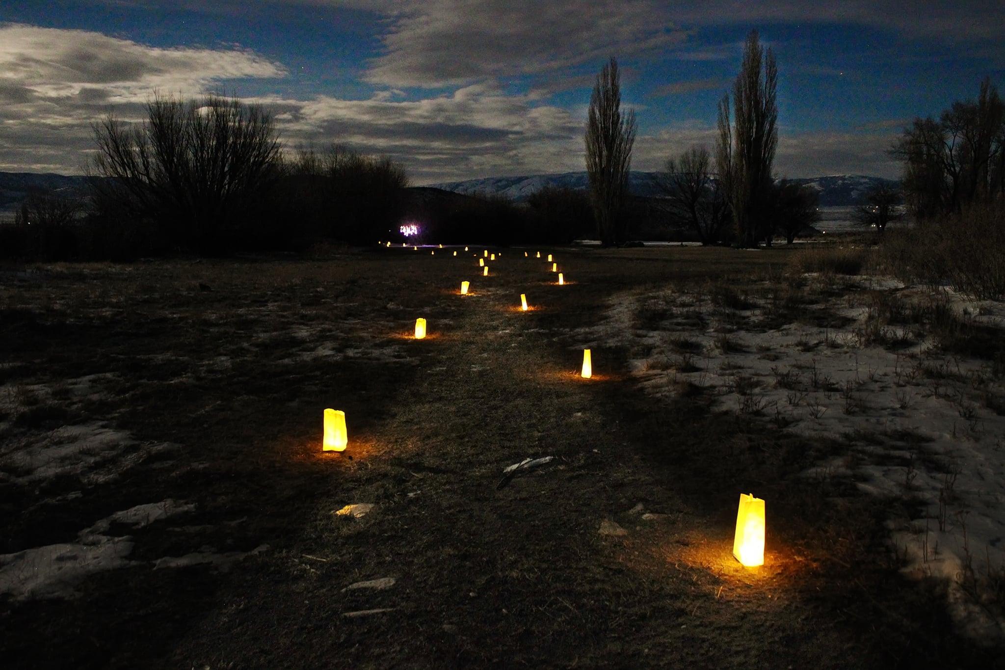 Paper luminary bags glow warmly lining a path through the darkness.