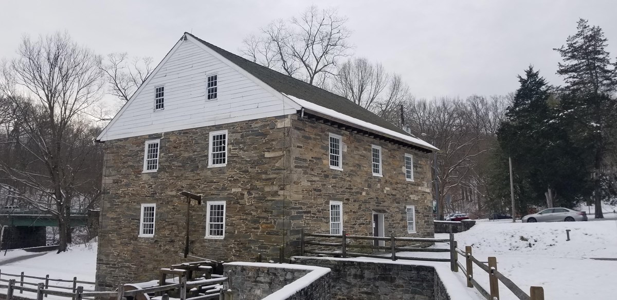 a three-story stone mill surrounded by a snowy landscape