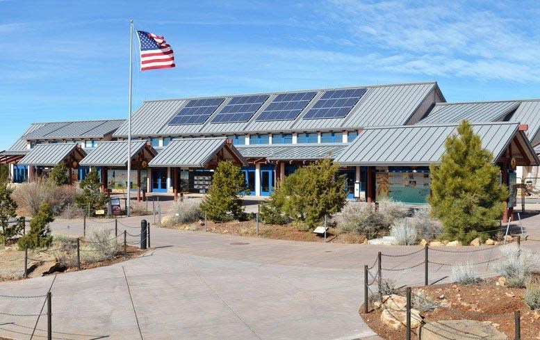 a large, curved visitor center building with blue doors and solar panels on a gray sloping roof.