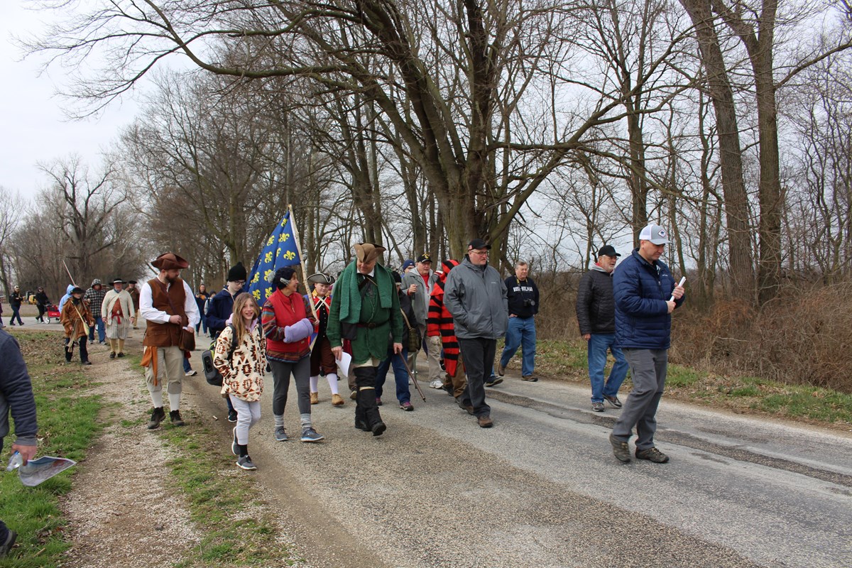 A group of people in historic dress and modern dress walking down a road