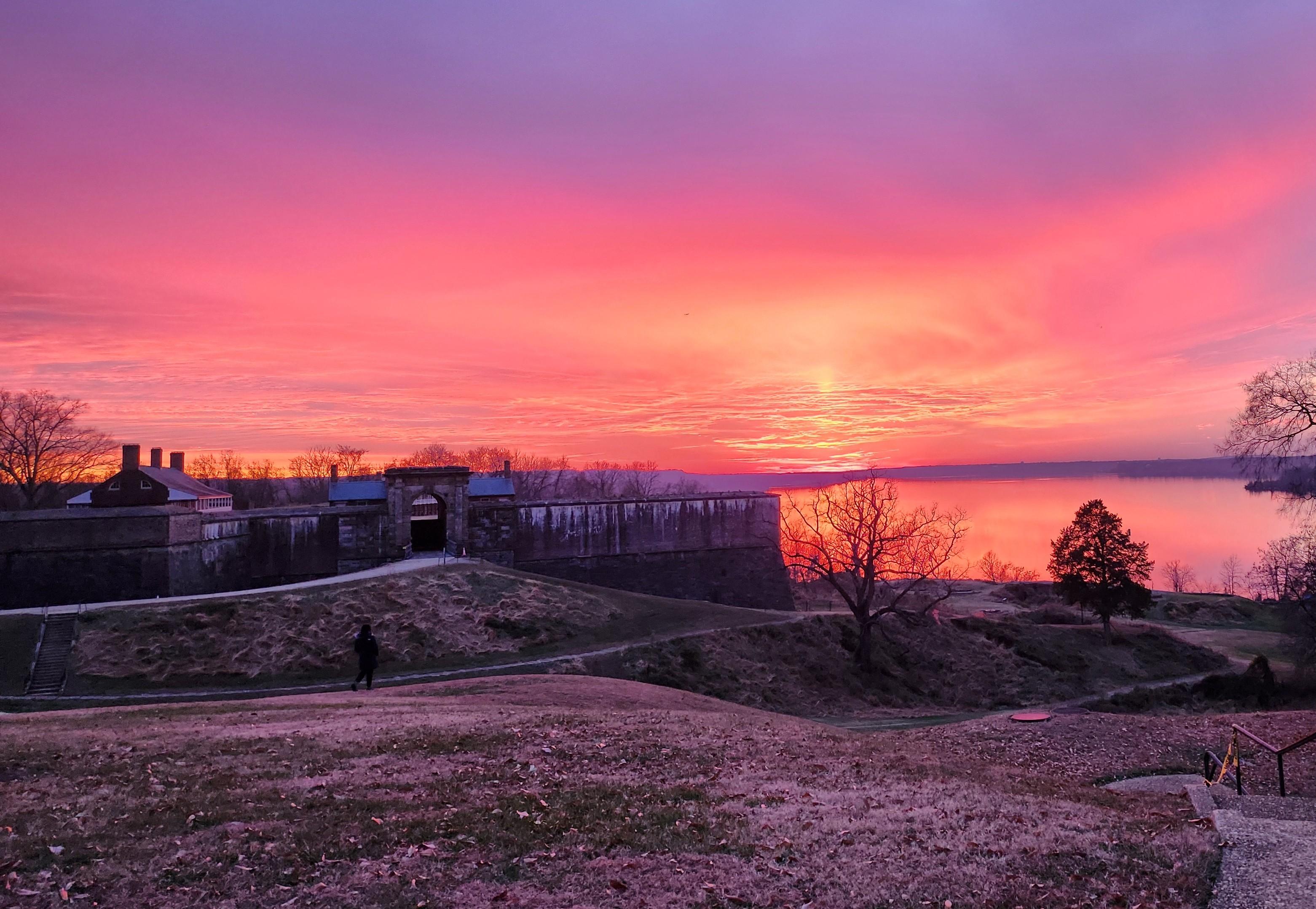 Landscape portrait of Fort Washington, the horizon is a mix of orange, pink and bue