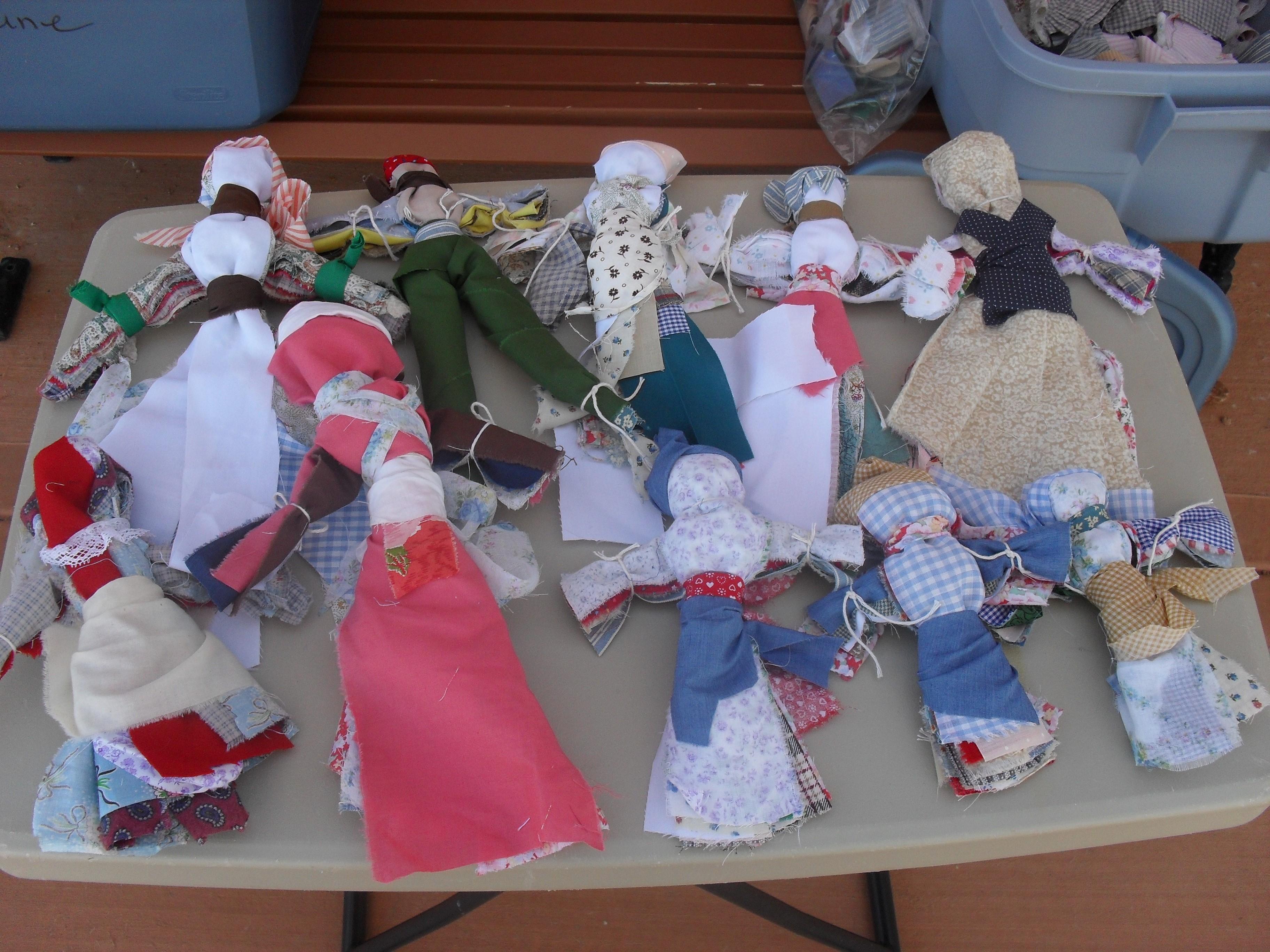 A variety of homemade rag dolls on a table
