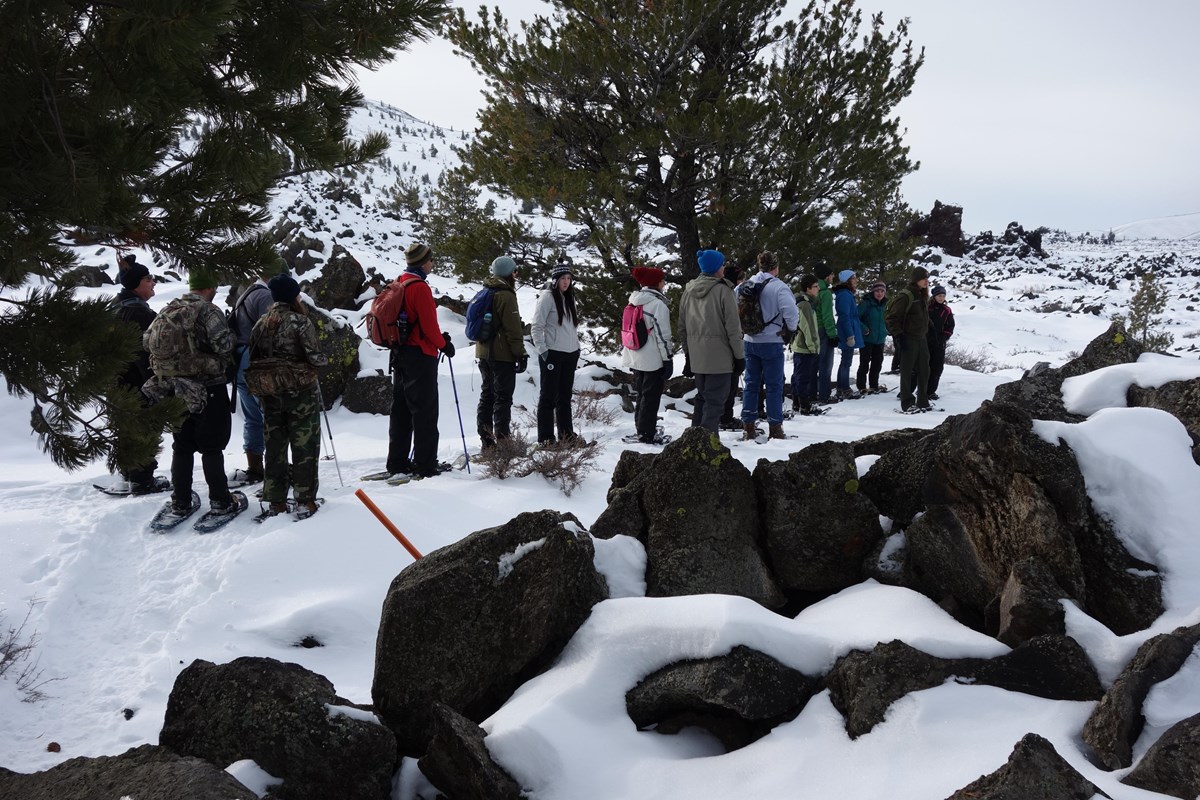Snowshoers with trees and lava rock