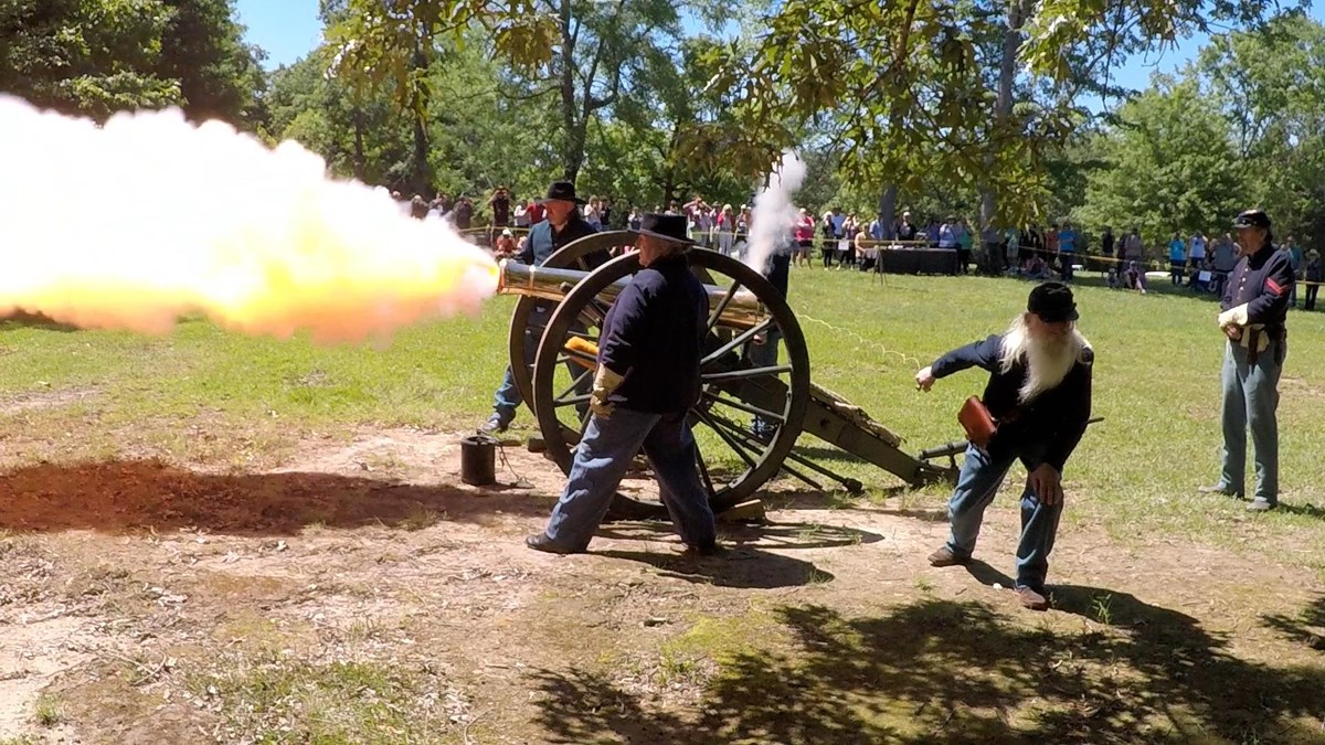 Living historians in Union uniforms fire a cannon.