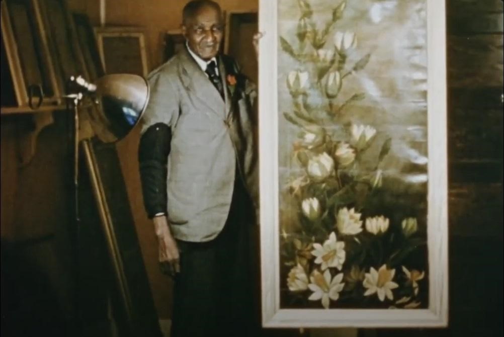 George Washington Carver standing with a large painting of flowers