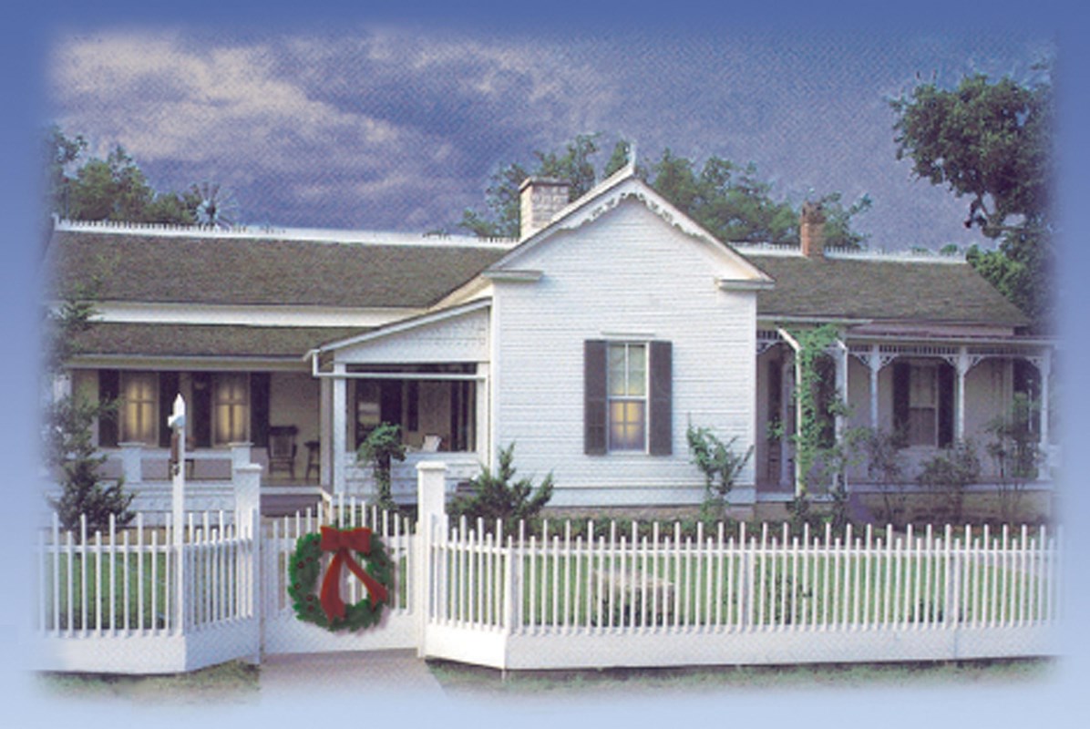 A wreath decorates the front gate of the Boyhood Home as lamps shine in the windows.