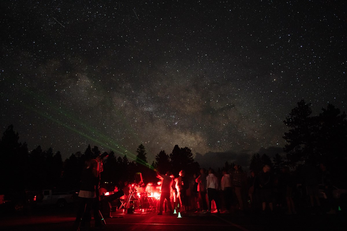 A nighttime photo of a group of people gathered to look at the stars.