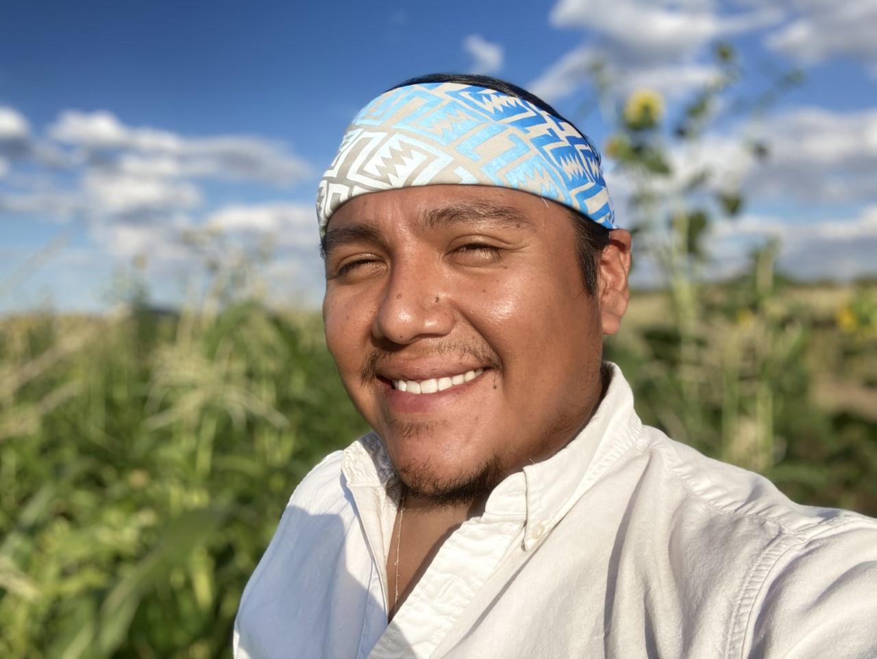 A man smiling in front of a field.