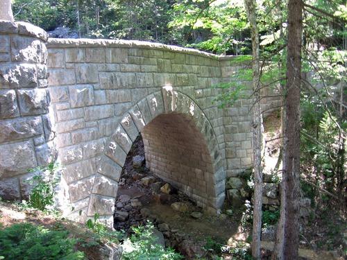 A stone bridge made from granite with water flowing underneath.