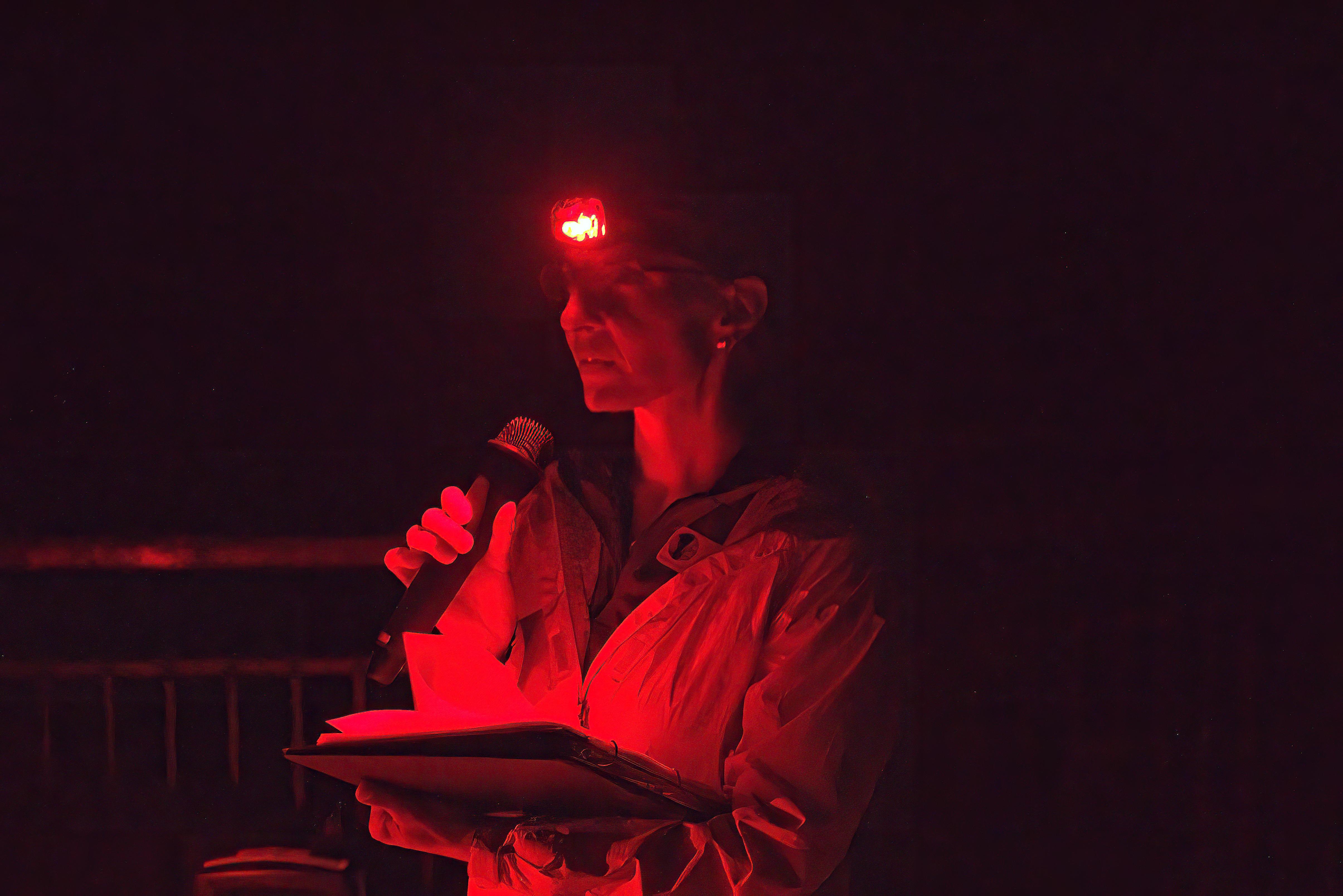 A woman reading in the dark under a red head lamp