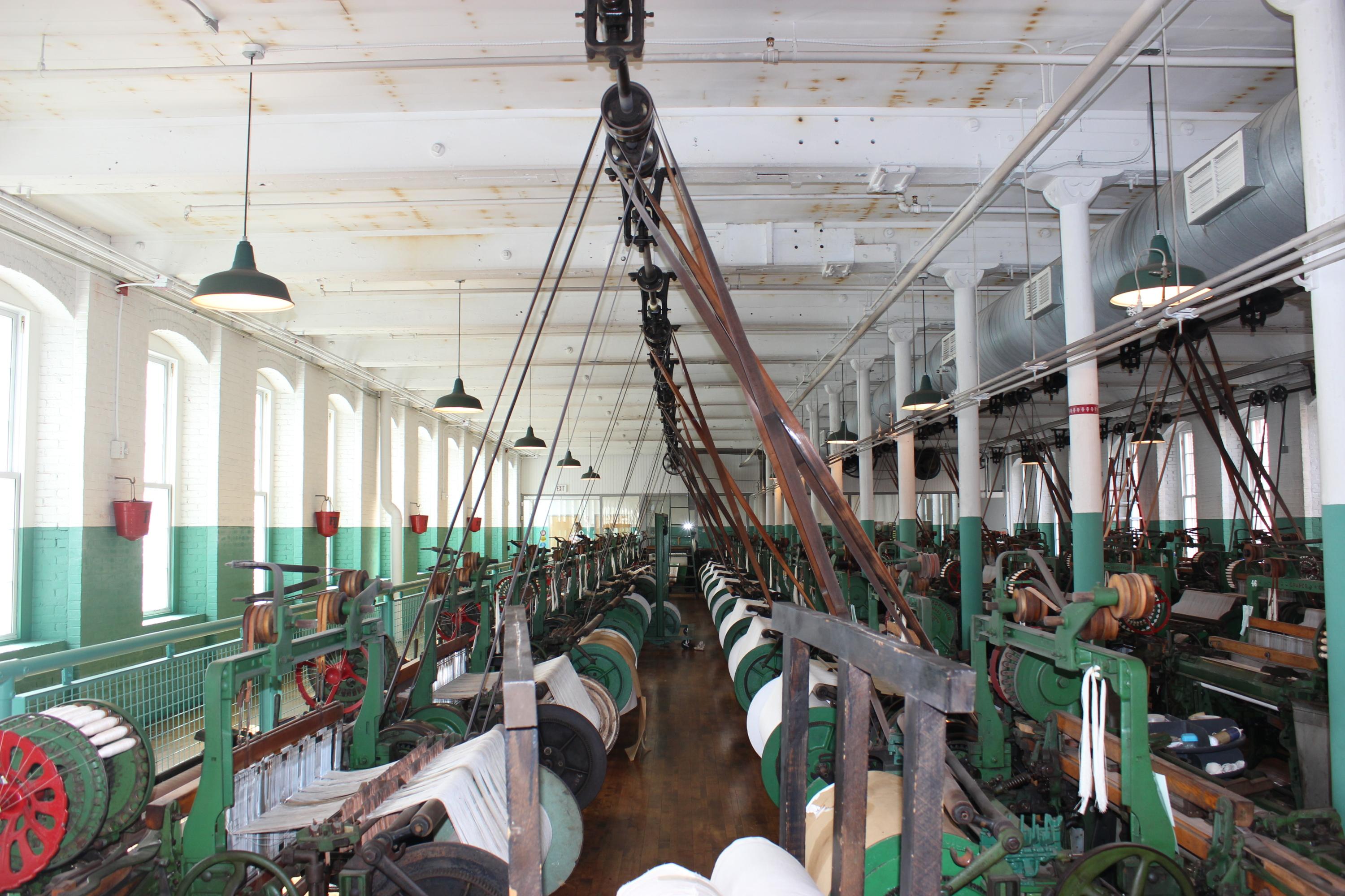 Photograph of a room full of machines, green and red painted looms.