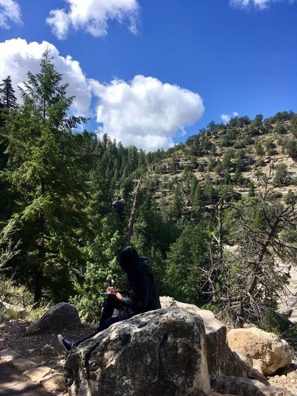 A visitor sits on a rock composing poetry at Walnut Canyon National Monument.