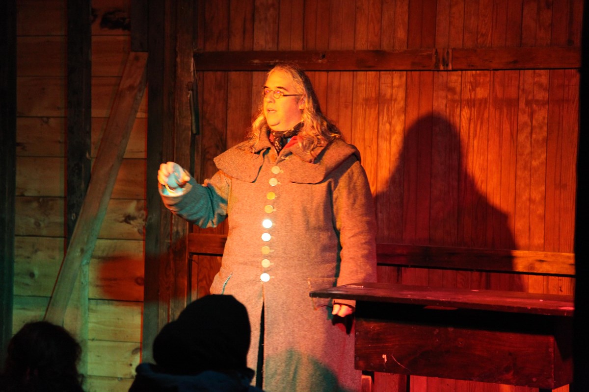 Park Ranger dressed in a gray colonial overcoat on a lit stage