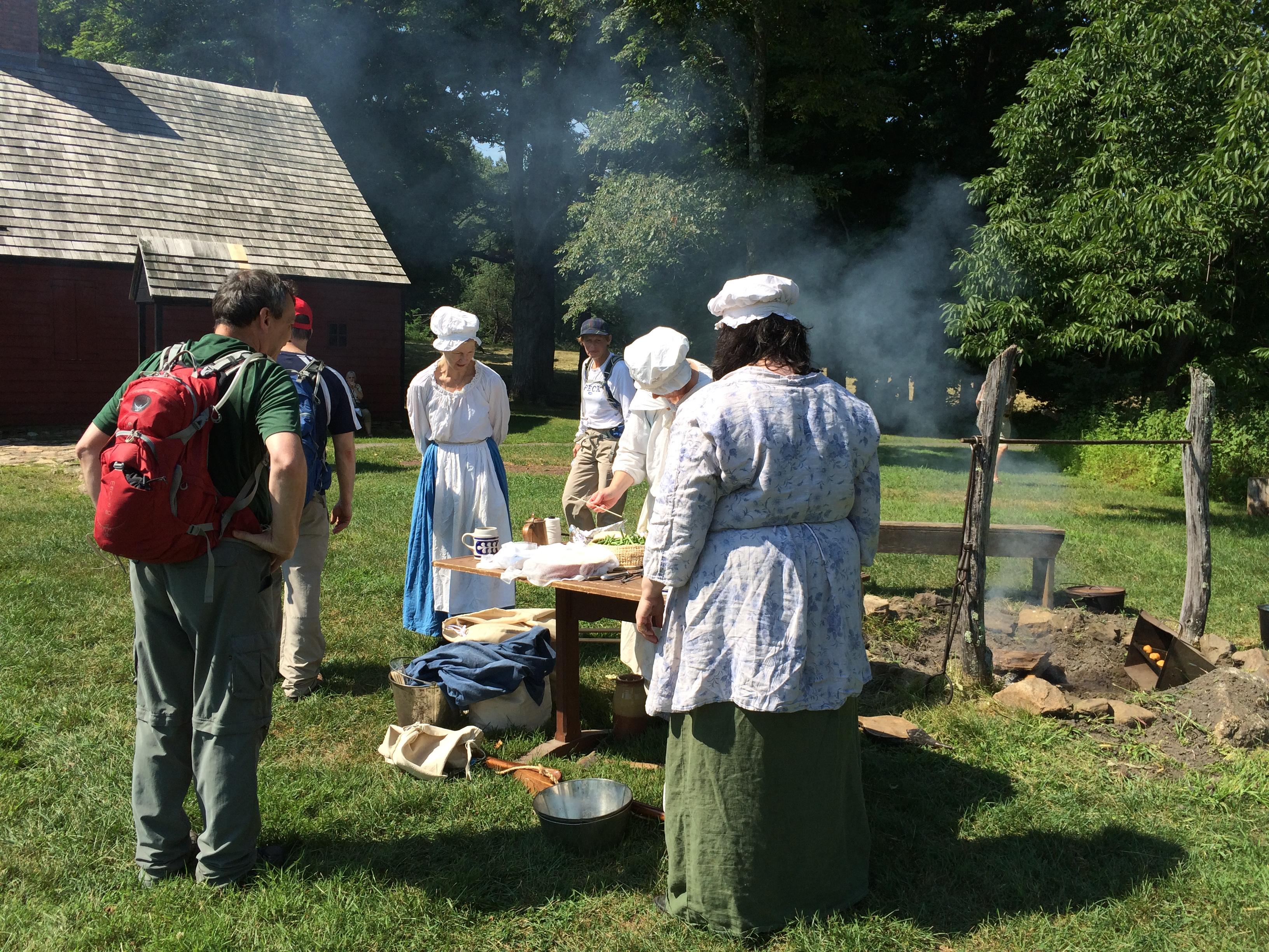Women in colonial clothing giving a demonstration to tourists.
