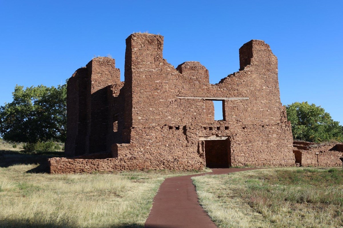 Red sandstone church ruins against a blue sky background.