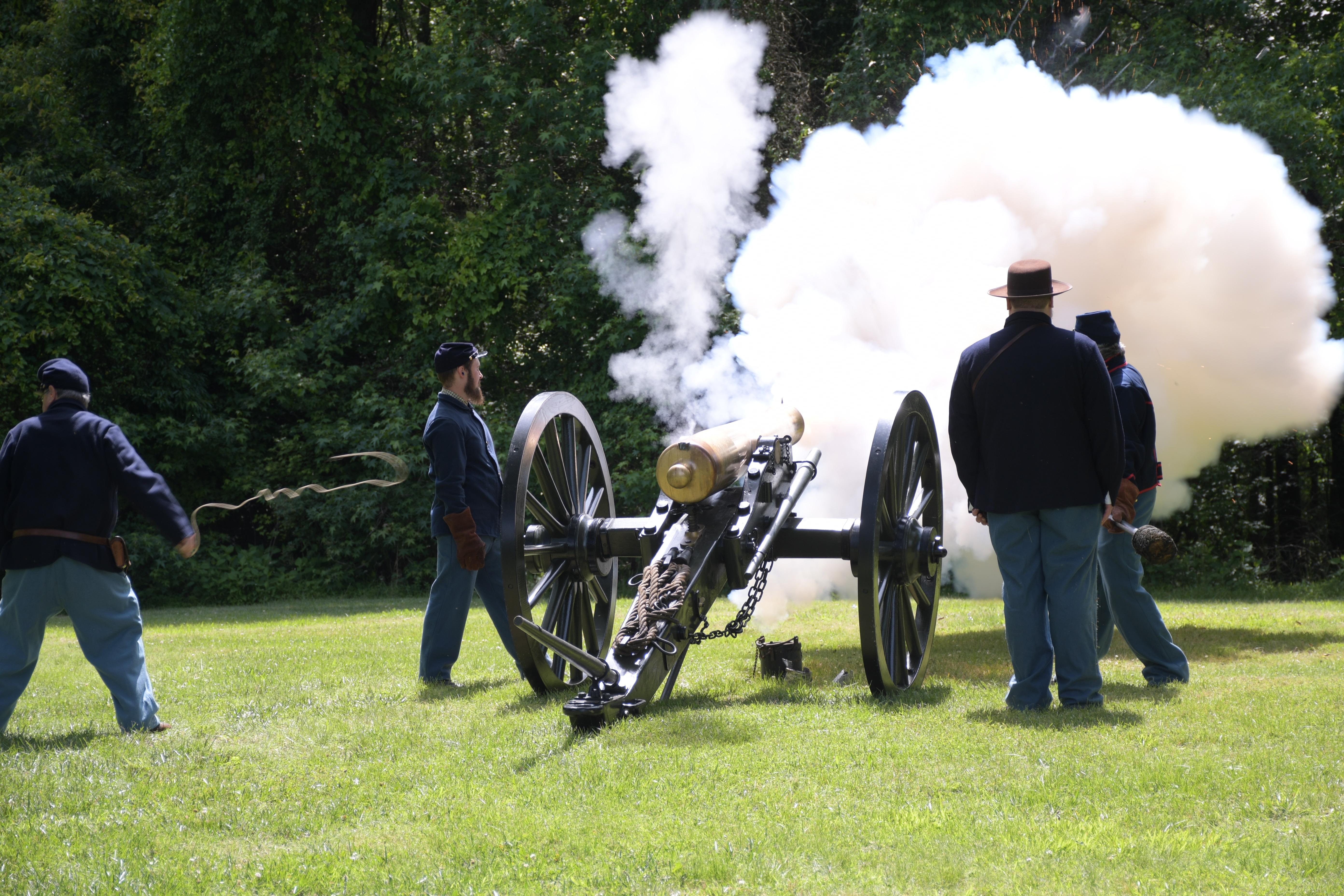 Four men in blue uniforms fire a cannon.