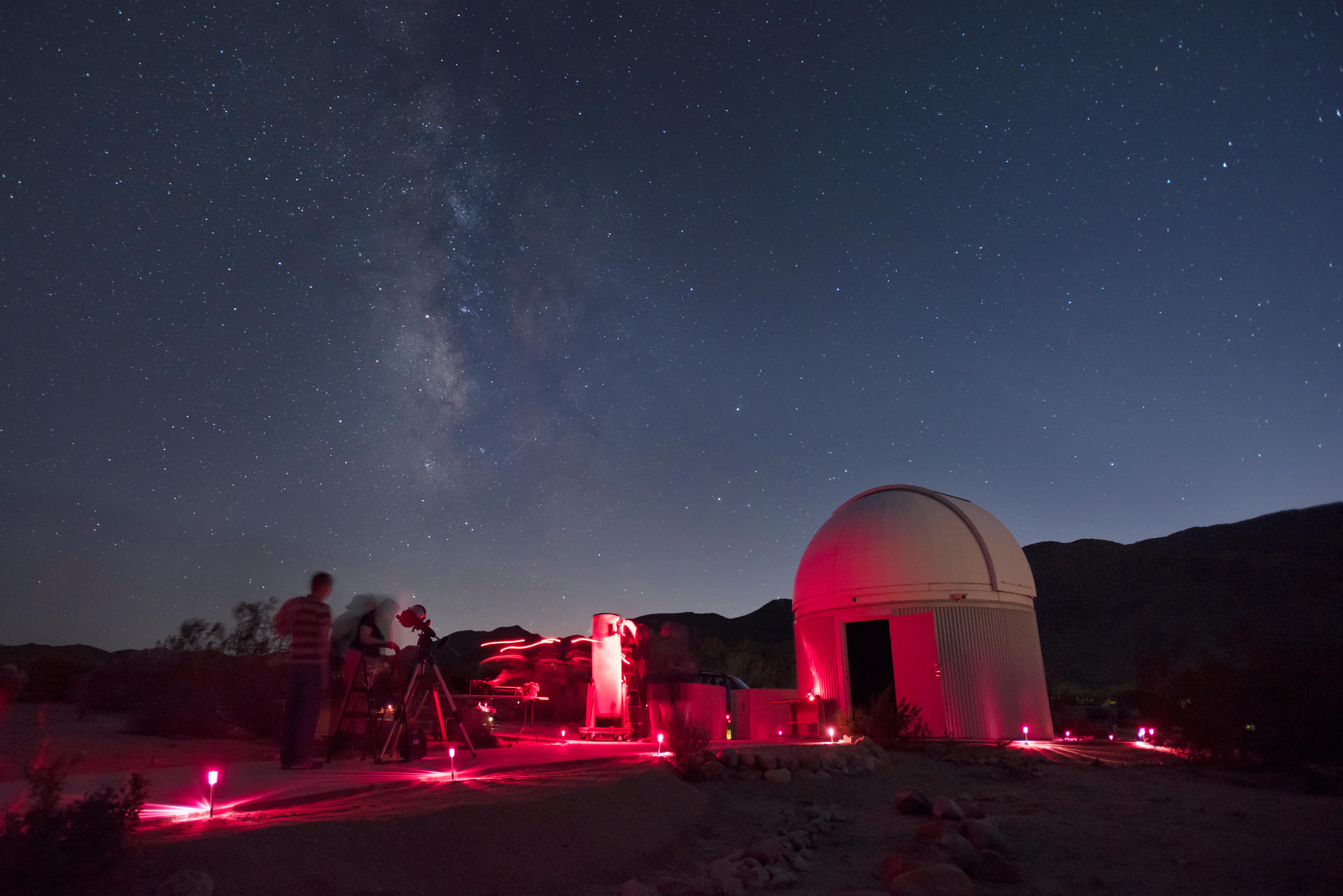A telescope, bathed in red light, and the night sky above