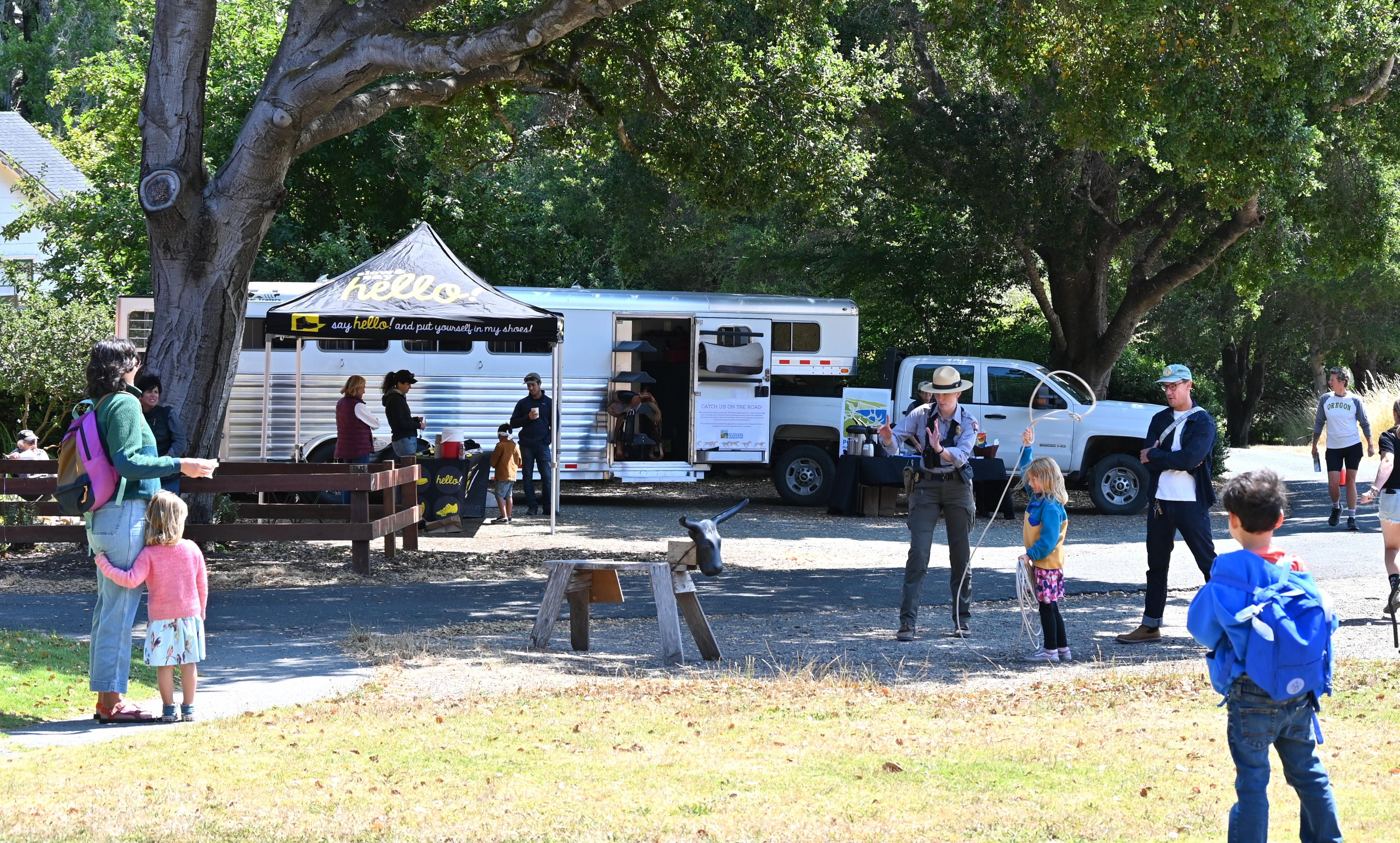 A few people look on as a ranger teaches a child how to throw a lasso.