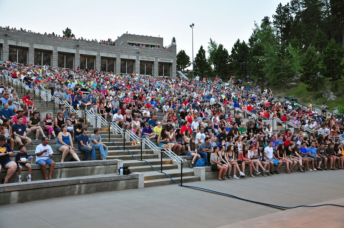 Visitors sitting in the amphitheater waiting for the Evening Lighting Ceremony to begin.