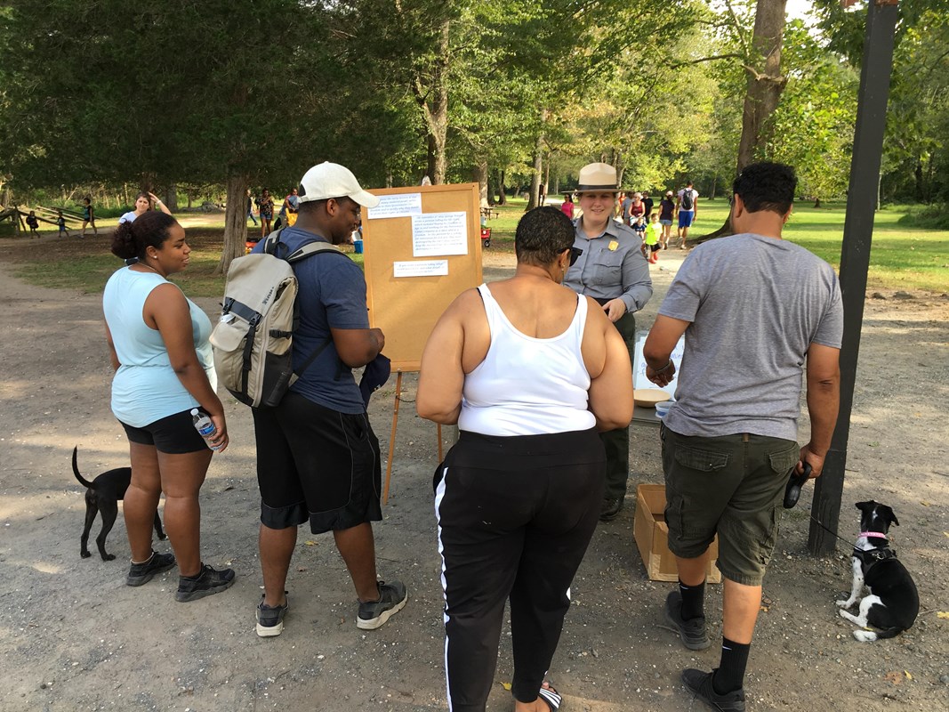 Park Ranger faces a group while presenting with a cork board