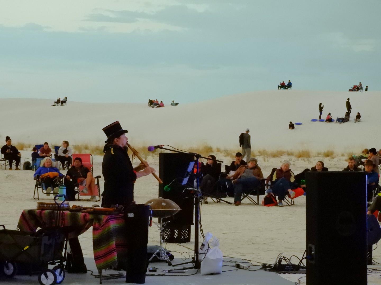 A musician plays the flute for a crowd of people