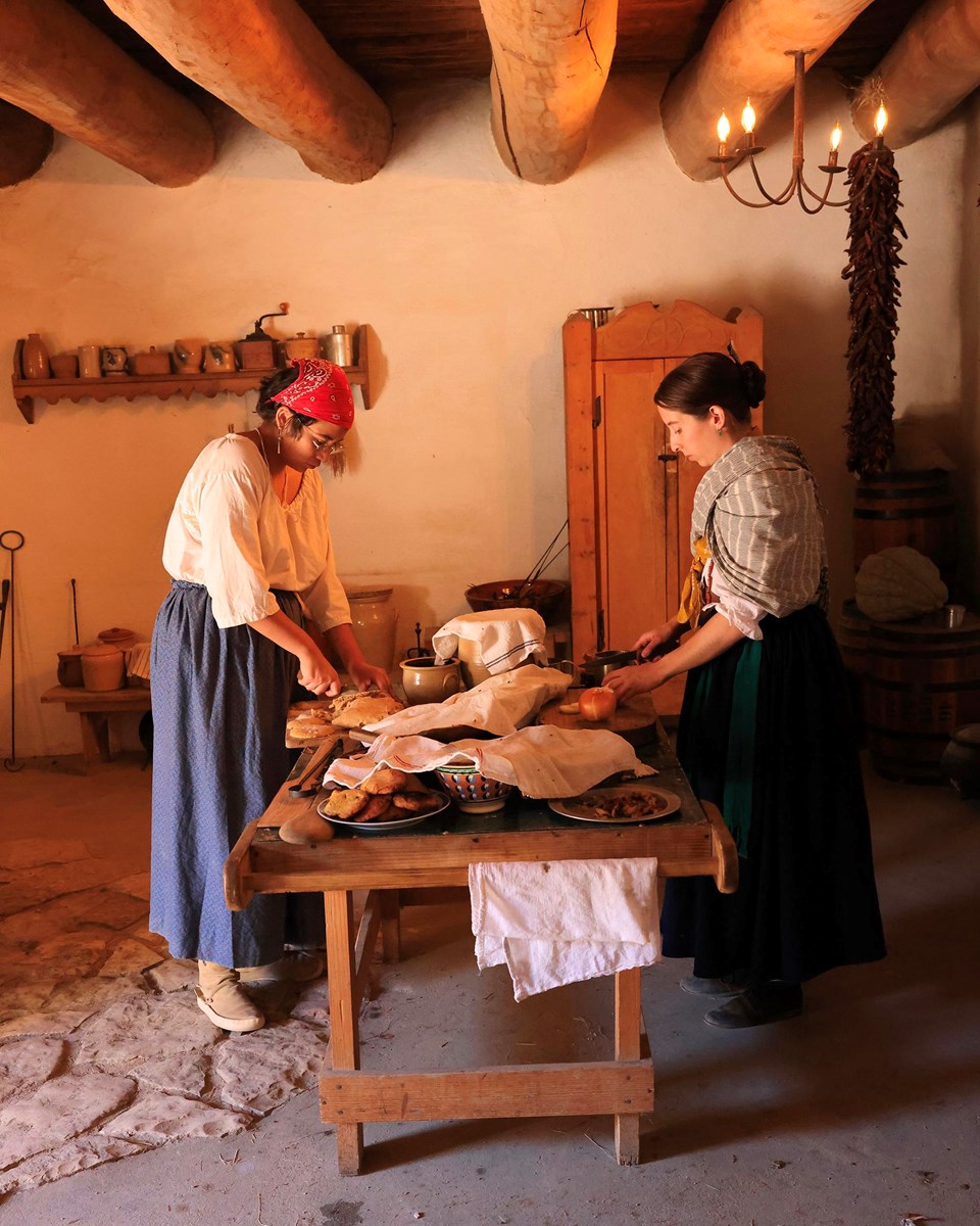 Two Living Historians (Domestics) in 1843 period clothing preparing food