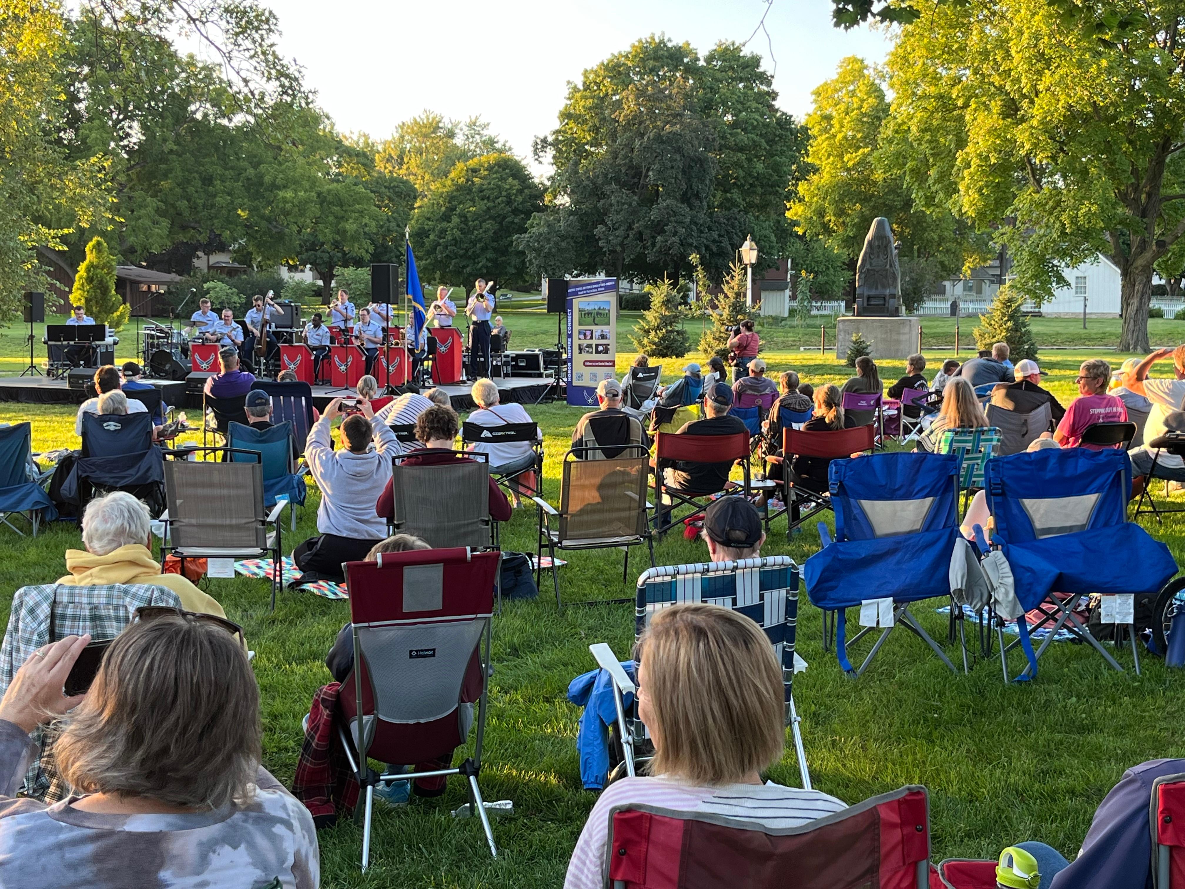 People sitting on lawn chairs listen to the Air Force band perform