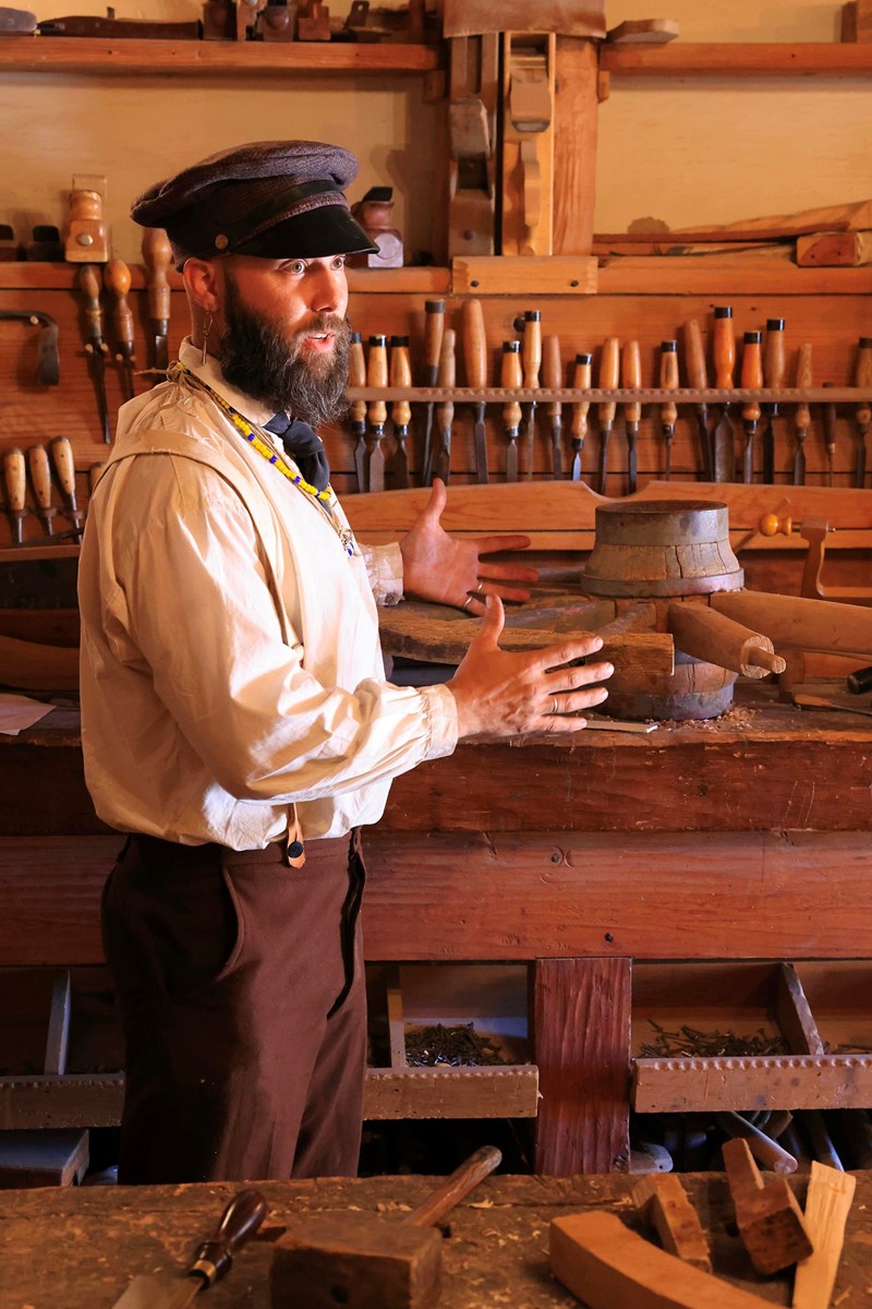 Living Historian (craftsman) in 1843 period clothing in carpenter’s shop explaining his trade