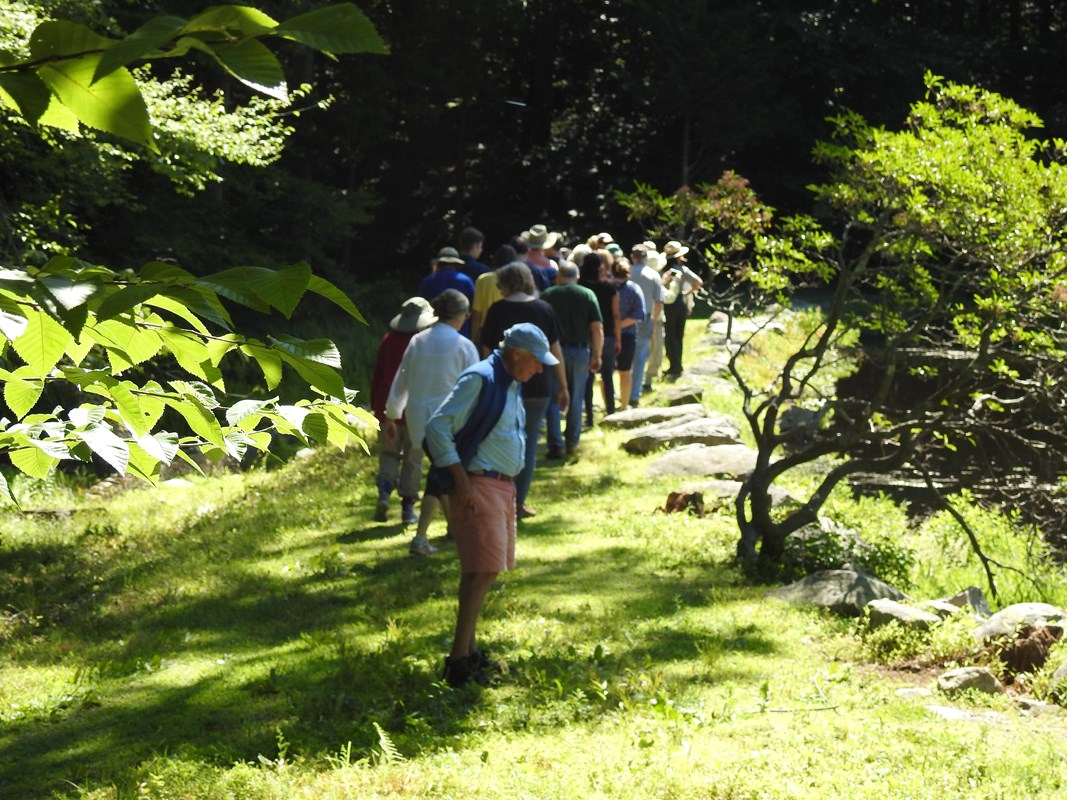 A group of people in a line follow a ranger around a pond.