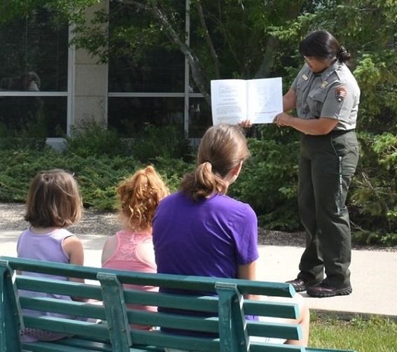 Ranger reading a book outside to a woman and 2 children
