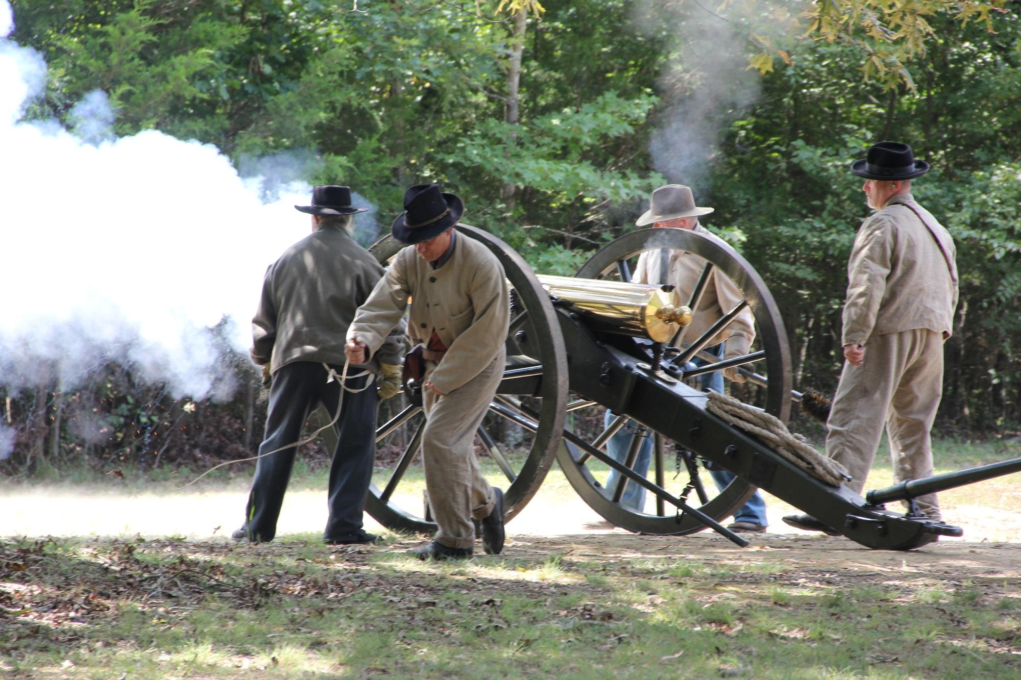 Smoke belches from a bronze cannon as living historians fire the gun.