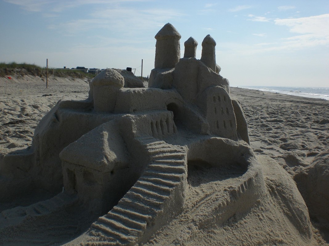 A sandcastle created on a sandy beach under a blue sky