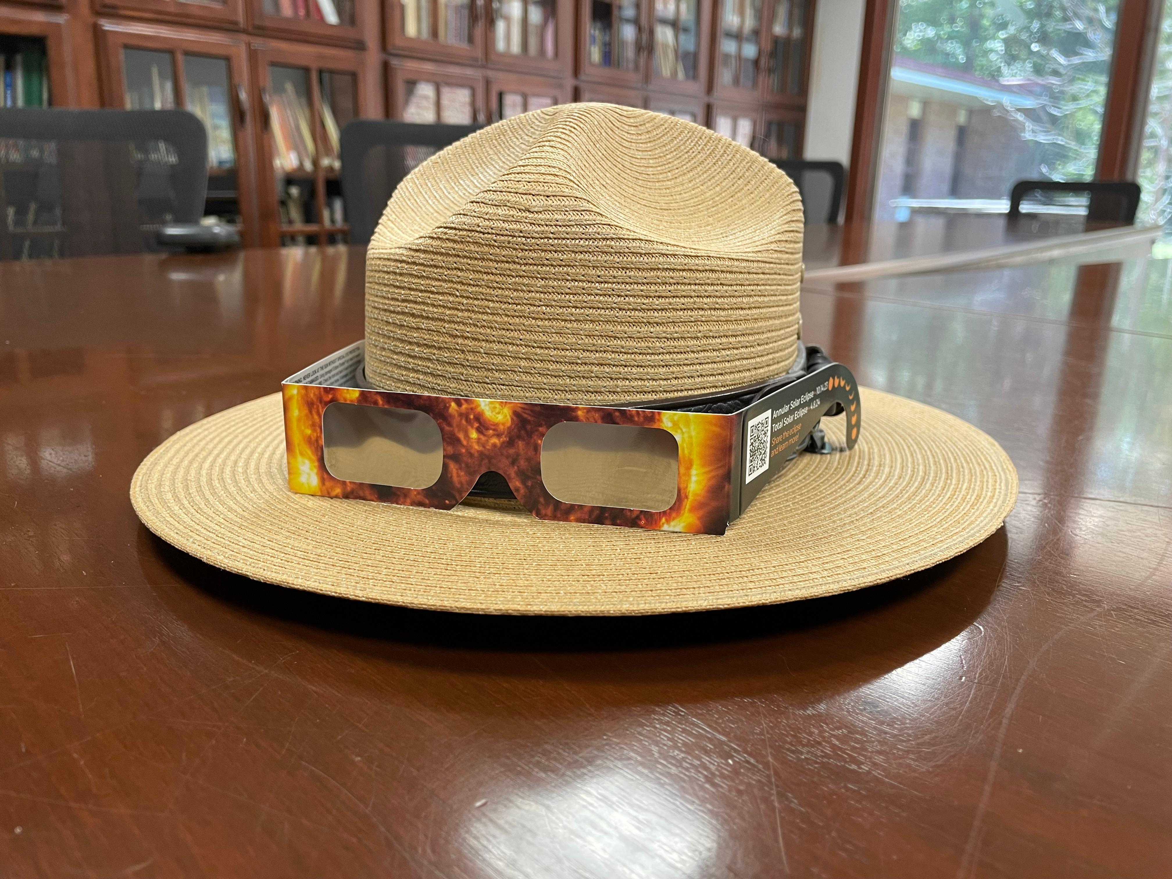 A National Park Service flat hat with eclipse glasses sitting on a table.