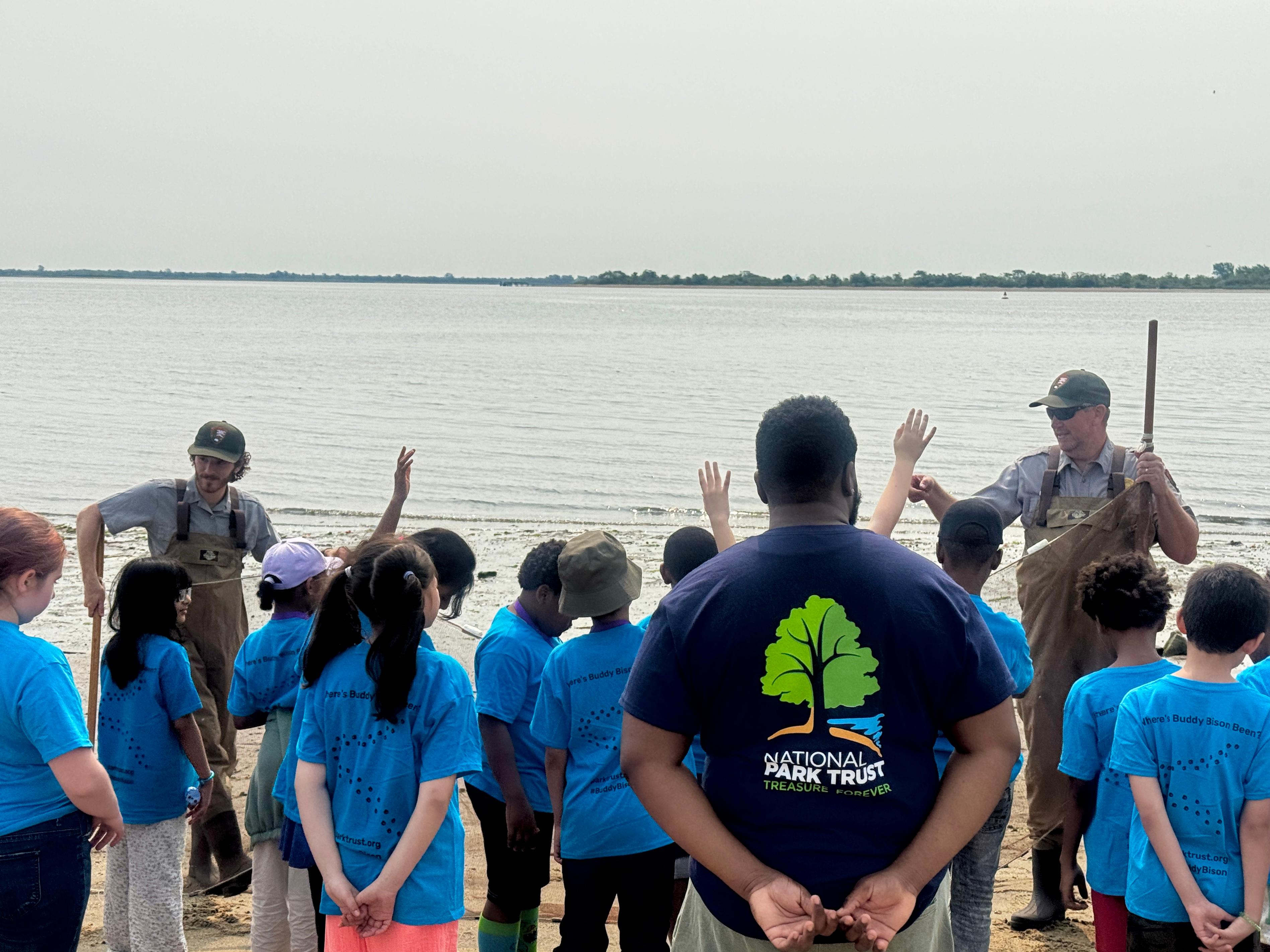 Two park rangers holding a seining net in front of a captive audience of students.